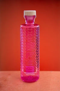 Downpour Pink Grapefruit Gin, bright pink embossed glass bottle against a bright orange background 