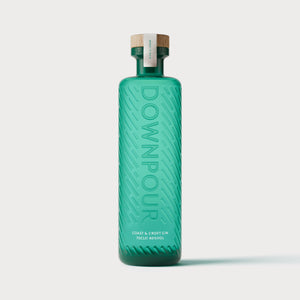 Downpour Coast & Croft Gin. a turquoise bottle embossed with graphic rain pattern and the word DOWNPOUR. It has a wooden stopper and the words 'Coast & Croft Gin' screen printed on it 